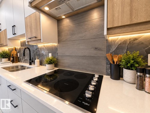 Quartz countertops with integrated cooktop, dual-tone cabinetry, undermount double-basin sink with matte black faucet, and patterned backsplash - 1312 35 Street Nw, Edmonton, AB 