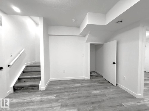 Wood-finish flooring, white walls, and a staircase with a white handrail - 1312 35 Street Nw, Edmonton, AB 
