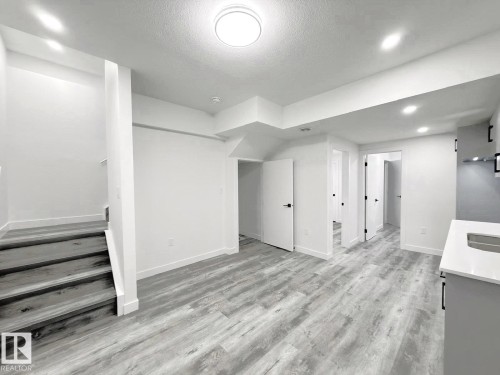 Light wood-finish flooring throughout, recessed lighting, and a contemporary flush-mount ceiling fixture - 1312 35 Street Nw, Edmonton, AB 