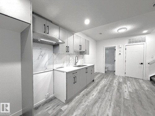 Kitchenette featuring light gray cabinetry, white countertops, and a white marble-look backsplash - 1312 35 Street Nw, Edmonton, AB 
