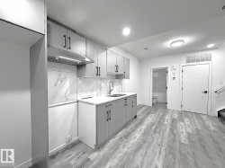 Kitchenette featuring light gray cabinetry, white countertops, and a white marble-look backsplash - 