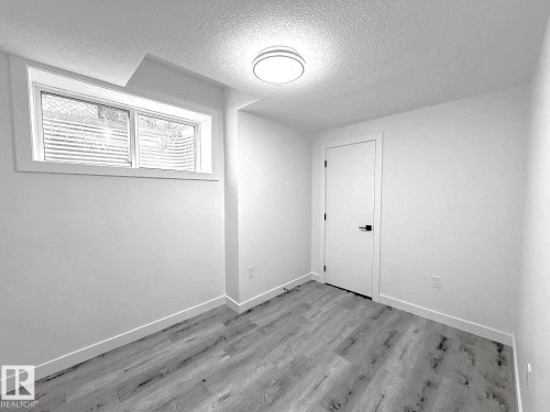 Recessed window, ceiling-mounted light fixture, wood-finish flooring, white painted walls, white door with black hardware - 1312 35 Street Nw, Edmonton, AB 