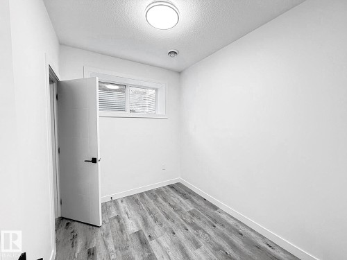 Recessed window with white blinds, wood-finish flooring, white walls, and a flush mount ceiling light - 1312 35 Street Nw, Edmonton, AB 