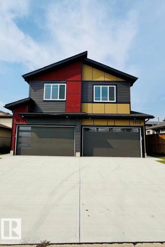 Modern duplex exterior with multi-color siding, contrasting trim, white-framed windows, and two garage doors - 1312 35 Street Nw, Edmonton, AB 