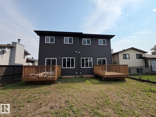 Black horizontal siding with white trim windows and two separate wood decks - 1312 35 Street Nw, Edmonton, AB 