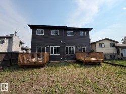 Black horizontal siding with white trim windows and two separate wood decks - 