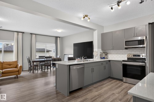 Modern kitchen featuring gray cabinetry with stainless steel hardware, white subway tile backsplash, and integrated stainless steel appliances including a built-in microwave and wall oven - 17 Spruce Ridge Cove, Spruce Grove, AB - Indoor Photo Showing Kitchen With Double Sink