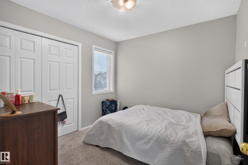 Spacious secondary bedroom featuring neutral wall finishes, carpeted flooring, a large closet with six-panel doors, and a window with natural light - 17 Spruce Ridge Cove, Spruce Grove, AB - Indoor Photo Showing Bedroom