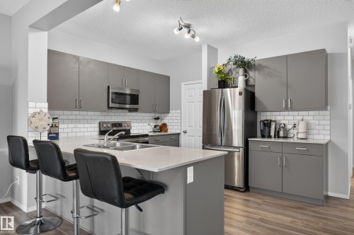 Kitchen featuring full-height gray cabinetry, stainless steel appliances, a subway tile backsplash, and an island with a built-in sink - 17 Spruce Ridge Cove, Spruce Grove, AB - Indoor Photo Showing Kitchen With Double Sink With Upgraded Kitchen