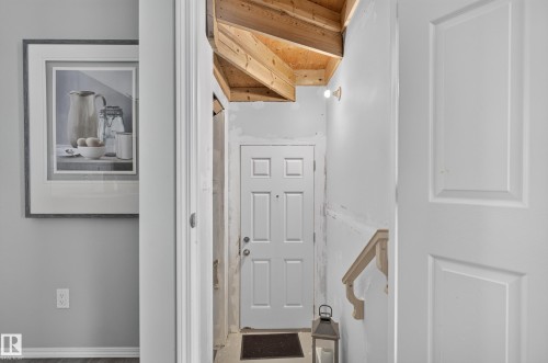 Bright entryway with crisp white six-panel door, wooden stair treads with handrail, and vaulted wooden ceiling detail - 17 Spruce Ridge Cove, Spruce Grove, AB - Indoor Photo Showing Other Room