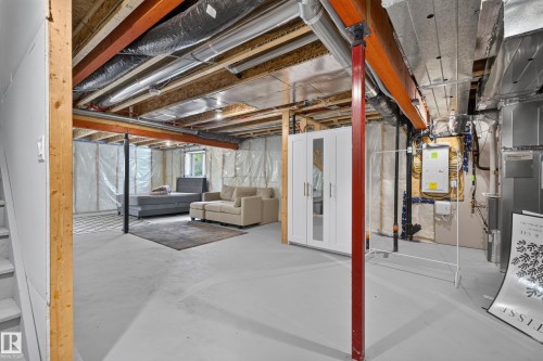 Expansive industrial-style loft featuring exposed beam ceiling with steel bracing, polished concrete flooring throughout, and soaring ceiling heights - 17 Spruce Ridge Cove, Spruce Grove, AB - Indoor Photo Showing Basement