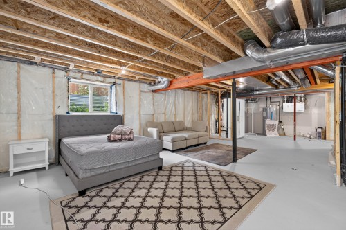 Unfinished basement with exposed wood joists, structural support beams, and a window with blinds - 17 Spruce Ridge Cove, Spruce Grove, AB - Indoor Photo Showing Basement
