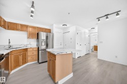Kitchen featuring wood cabinetry, white countertops, stainless steel refrigerator, and an island - 