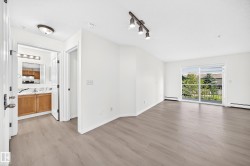 Open-concept living area with light-toned wood-finish flooring and white baseboards - 