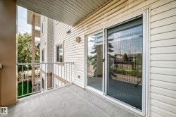 Private balcony featuring durable outdoor carpeting, white metal railing, and a sliding glass door with an integrated screen - 