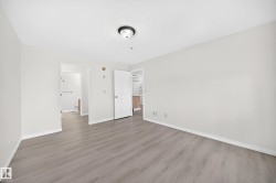 Spacious room with light wood-finish flooring, white baseboards, and a neutral wall color - 