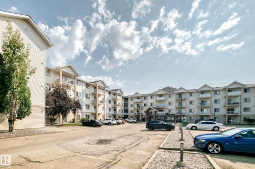 Multi-story residential complex featuring private balconies, individual window units, pitched roofs, and a central entry canopy - #214 245 Edwards Dr Sw, Edmonton, AB - Outdoor With Balcony With Facade