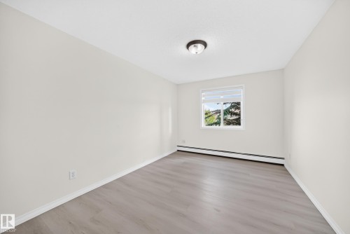 Room featuring light gray wood-finish flooring, white baseboards, and neutral wall paint - #214 245 Edwards Dr Sw, Edmonton, AB - Indoor Photo Showing Other Room