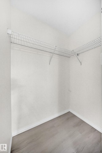Walk-in closet featuring wire shelving, light wood-finish flooring, and white baseboards - #214 245 Edwards Dr Sw, Edmonton, AB - Indoor With Storage
