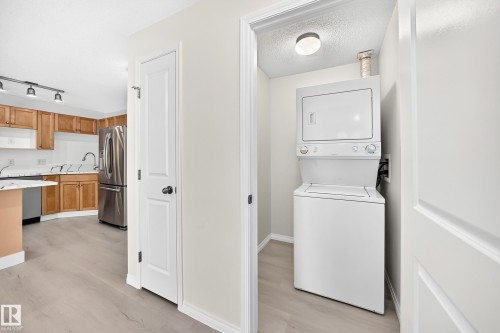 Dedicated laundry closet featuring a stacked washer and dryer - #214 245 Edwards Dr Sw, Edmonton, AB - Indoor Photo Showing Other Room