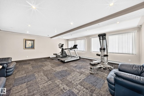 Spacious recreation room featuring recessed lighting and a drop ceiling with decorative beam - #214 245 Edwards Dr Sw, Edmonton, AB - Indoor Photo Showing Gym Room