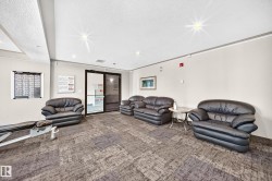 Entryway lounge featuring a patterned carpet, multiple dark leather sofas and armchairs, a glass-top side table, and double glass entry doors - 