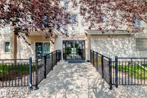 Building exterior with light-toned horizontal siding and glass entry doors - #214 245 Edwards Dr Sw, Edmonton, AB - Outdoor