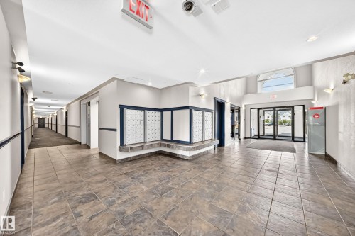Spacious lobby featuring large format tile flooring and an arched transom window above the entrance - #214 245 Edwards Dr Sw, Edmonton, AB - Indoor Photo Showing Other Room