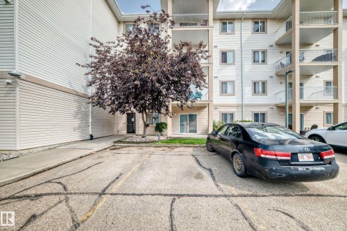Multi-story residential building featuring light-colored siding and a prominent entrance - #214 245 Edwards Dr Sw, Edmonton, AB - Outdoor With Balcony