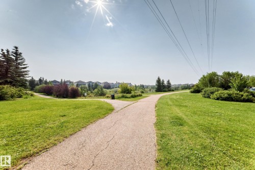 Paved pathways meander through expansive green spaces - #214 245 Edwards Dr Sw, Edmonton, AB - Outdoor With View