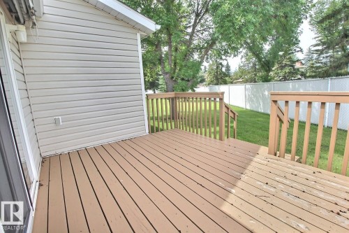 Outdoor wood-finish deck with wood railings, sliding glass door access, vinyl siding, and a fenced backyard with mature trees - 8146 27 Avenue Nw, Edmonton, AB - Outdoor With Deck Patio Veranda With Exterior