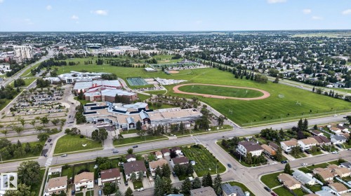 Aerial overview of a residential area featuring a large institutional building with an expansive green field, a running track, and tennis courts - 8146 27 Avenue Nw, Edmonton, AB - Outdoor With View