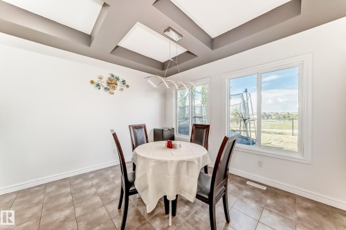 Dining space featuring a tray ceiling with recessed lighting, large windows, tile flooring, and a modern chandelier - 2812 12 Street Nw, Edmonton, AB - Indoor Photo Showing Dining Room