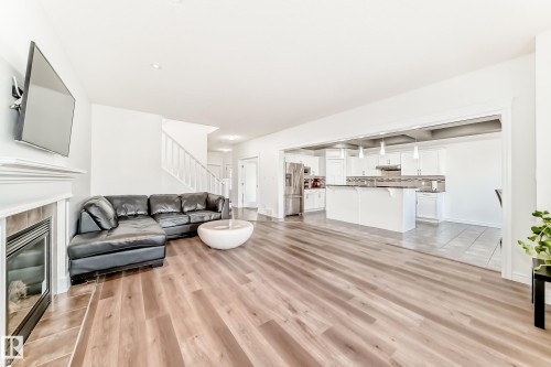 Spacious open-concept living area featuring wood-finish flooring, a fireplace with a tiled surround and white mantle, and white walls - 2812 12 Street Nw, Edmonton, AB - Indoor Photo Showing Living Room With Fireplace