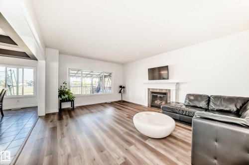 Spacious living area featuring wood-finish flooring, a traditional fireplace with a white mantel and tile surround, and large windows providing ample natural light - 2812 12 Street Nw, Edmonton, AB - Indoor Photo Showing Living Room With Fireplace