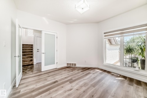 Bright room featuring wood-finish flooring and a large window with roller shades - 2812 12 Street Nw, Edmonton, AB - Indoor Photo Showing Other Room
