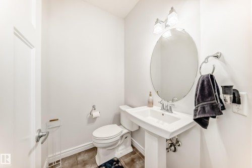 Pedestal sink with chrome hardware and an oval mirror, complemented by an overhead vanity light fixture - 2812 12 Street Nw, Edmonton, AB - Indoor Photo Showing Bathroom