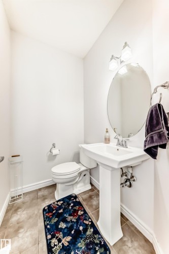 Pedestal sink with chrome faucet, oval mirror, and three-light vanity fixture - 2812 12 Street Nw, Edmonton, AB - Indoor Photo Showing Bathroom