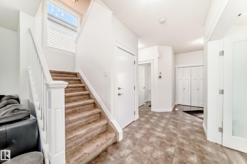 Entryway featuring a carpeted staircase with white railings, a window with blinds, and tile flooring - 2812 12 Street Nw, Edmonton, AB - Indoor Photo Showing Other Room