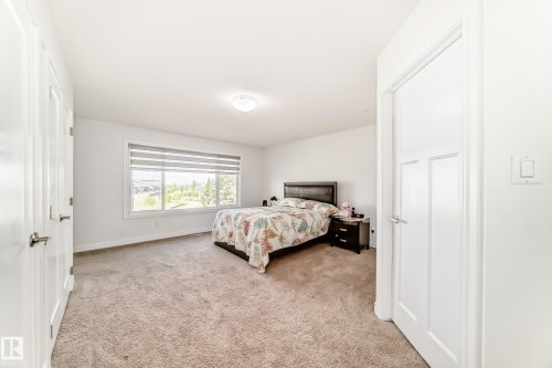 Spacious carpeted room featuring a large window with horizontal blinds, white interior doors, and a ceiling-mounted light fixture - 2812 12 Street Nw, Edmonton, AB - Indoor Photo Showing Bedroom