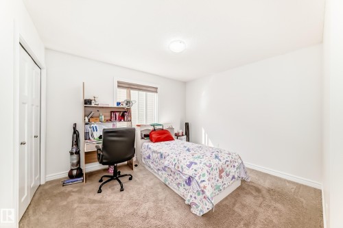 Carpeted room with a window featuring horizontal blinds, white baseboards, and a flush mount ceiling light - 2812 12 Street Nw, Edmonton, AB - Indoor Photo Showing Bedroom