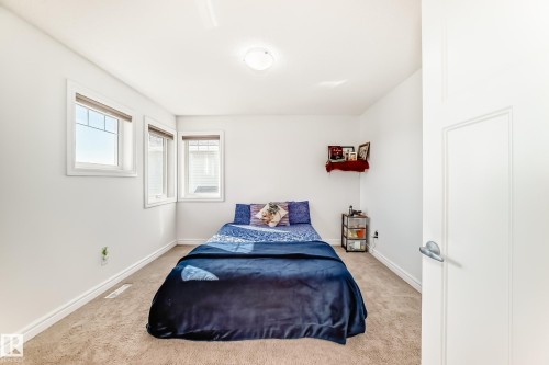 Light-filled room featuring neutral wall tones, plush carpet flooring, white trim, and a white interior door with a brushed nickel lever handle - 2812 12 Street Nw, Edmonton, AB - Indoor Photo Showing Bedroom