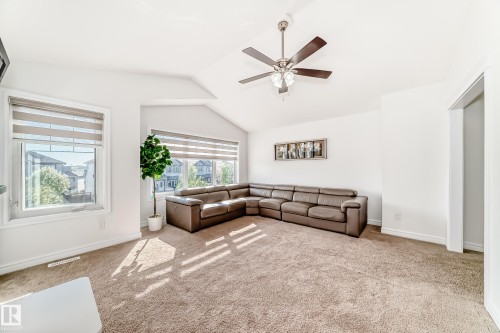 Carpeted living area featuring high vaulted ceilings, multiple windows with blinds, and a ceiling fan with integrated lighting - 2812 12 Street Nw, Edmonton, AB - Indoor