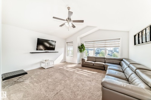 Spacious living area featuring vaulted ceilings, light-hued carpeting, a ceiling fan with integrated lighting, and multiple windows with horizontal blinds - 2812 12 Street Nw, Edmonton, AB - Indoor Photo Showing Living Room