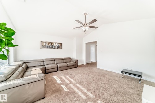 Spacious living area featuring vaulted ceilings, neutral-toned carpeting, a contemporary ceiling fan, and ample natural light from large windows - 2812 12 Street Nw, Edmonton, AB - Indoor