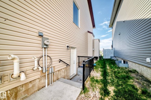 Side exterior featuring a concrete walkway, black metal railing, and a rear entry door - 2812 12 Street Nw, Edmonton, AB - Outdoor With Exterior