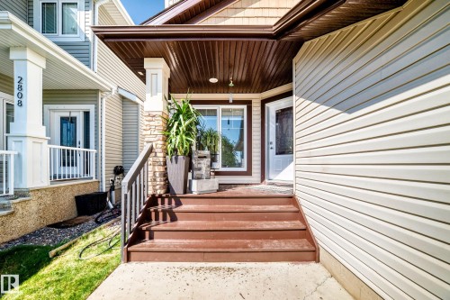 Entryway featuring a wood-finish staircase, stone pillar accents, and a white paneled door - 2812 12 Street Nw, Edmonton, AB - Outdoor With Deck Patio Veranda With Exterior