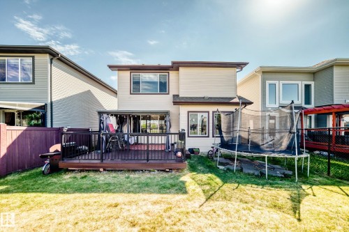Rear exterior featuring a spacious wood deck with black railings, a covered patio area, and a generous grassy yard - 2812 12 Street Nw, Edmonton, AB - Outdoor With Deck Patio Veranda