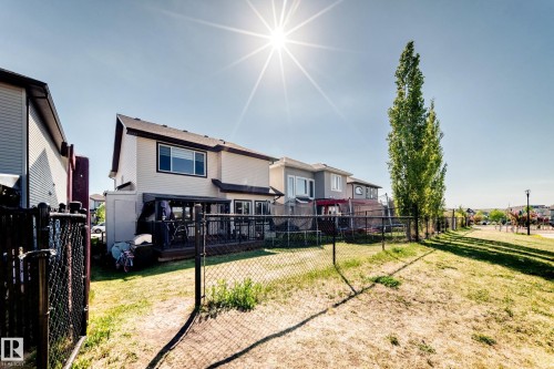 Rear exterior featuring a two-story residence with beige siding, a dark roof, and a ground-level deck - 2812 12 Street Nw, Edmonton, AB - Outdoor