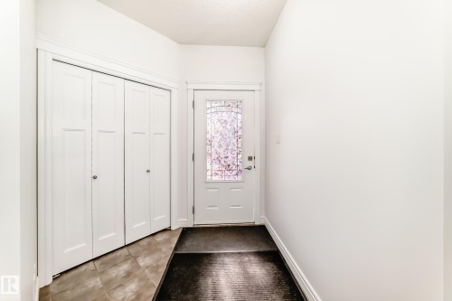 Entryway featuring a white door with decorative glass inserts, bi-fold closet doors, and tile flooring - 2812 12 Street Nw, Edmonton, AB - Indoor Photo Showing Other Room